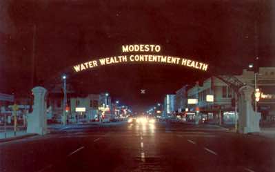 This is an actual photograph taken at night, as opposed to the earlier hand-painted postcard. The photo was tken sometime in the 1960s before the old buildings on the right were demolished.